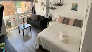 Moderni hotellihuone, jossa on suuri sänky, sohva, pieni pöytä ja televisio.