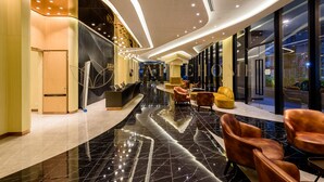 Eine moderne Lobby mit einer geschwungenen Rezeption, Ledersitzgelegenheiten und einem reflektierenden schwarzen Marmorboden.