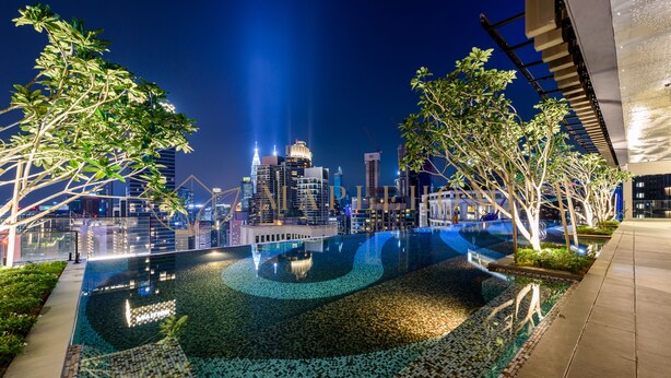 Ein Infinity-Pool mit Blick auf eine Stadtlandschaft, umgeben von Bäumen und moderner Architektur.