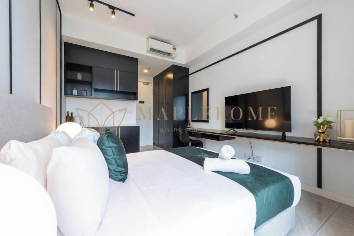 Una habitación de hotel moderna con cama, escritorio, televisión y kitchenette.