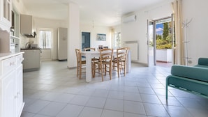 A spacious kitchen with a dining area, a balcony with a view, and a teal sofa. - 3438 Villa Poggio dei Loti by Barbarhouse (Cisternino)
