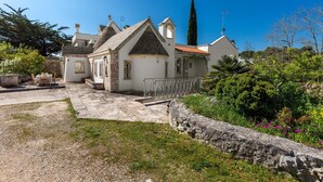A white building with a tiled roof, a stone wall, and a metal railing. - 3438 Villa Poggio dei Loti by Barbarhouse (Cisternino)