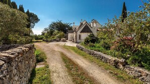 A stone-walled path leading to a building with a steeply pitched roof and a small bell tower. - 3438 Villa Poggio dei Loti by Barbarhouse (Cisternino)