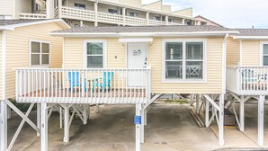 A beachfront hotel with a balcony, a door with a sign, and a parking sign.