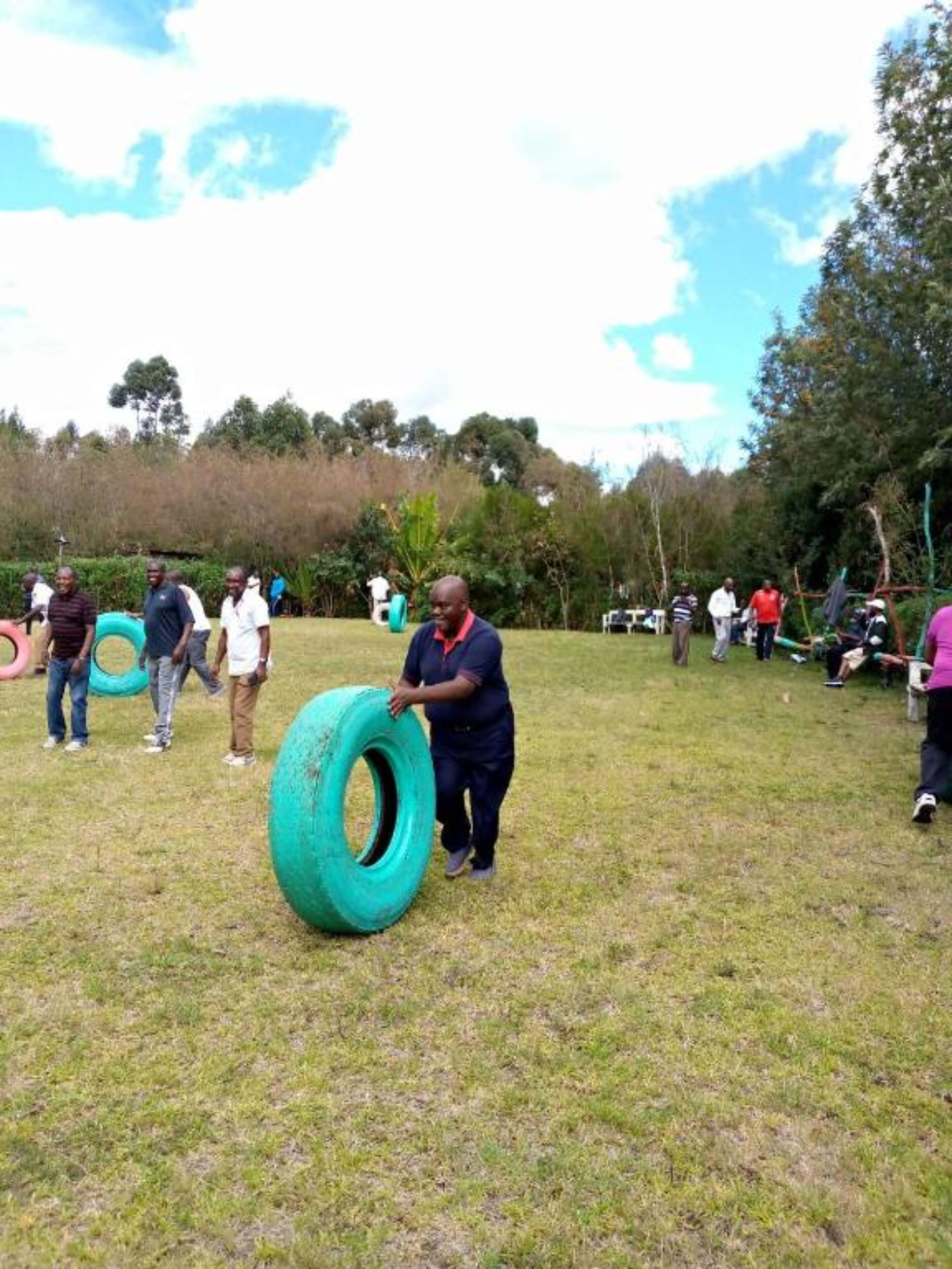 Un espacio al aire libre con césped, personas y neumáticos grandes.