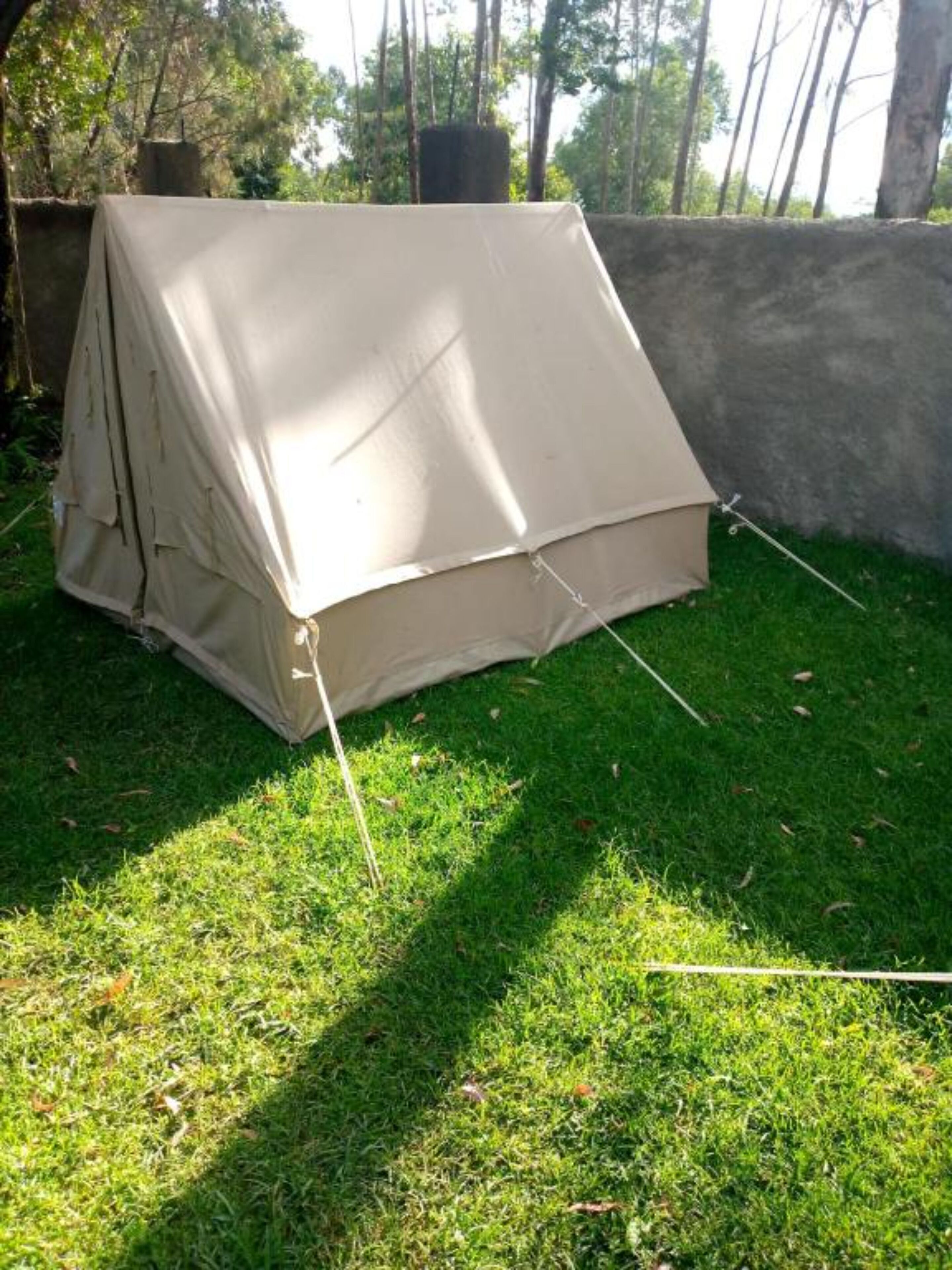 A tent set up on a grassy area with a concrete wall in the background.