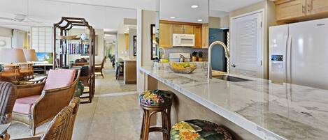 A modern kitchen with a marble countertop, wooden cabinets, and a built-in microwave.
