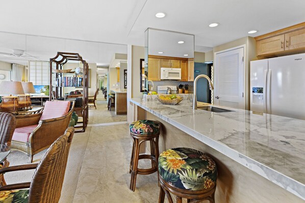 A modern kitchen with a marble countertop, wooden cabinets, and a built-in microwave.