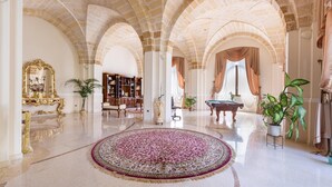 Un hall d’entrée spacieux, agrémenté d’un grand tapis décoratif, d’un piano à queue et d’une bibliothèque.