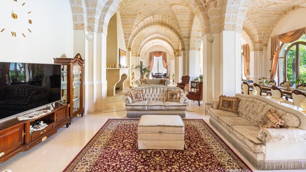 Un salon spacieux doté d’un grand téléviseur, d’un mobilier élégant et d’un plafond voûté.