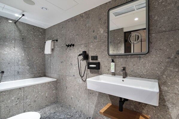 A modern bathroom with a white sink, a mirror, and a shower area. - Qubus Hotel Katowice (Katowice)