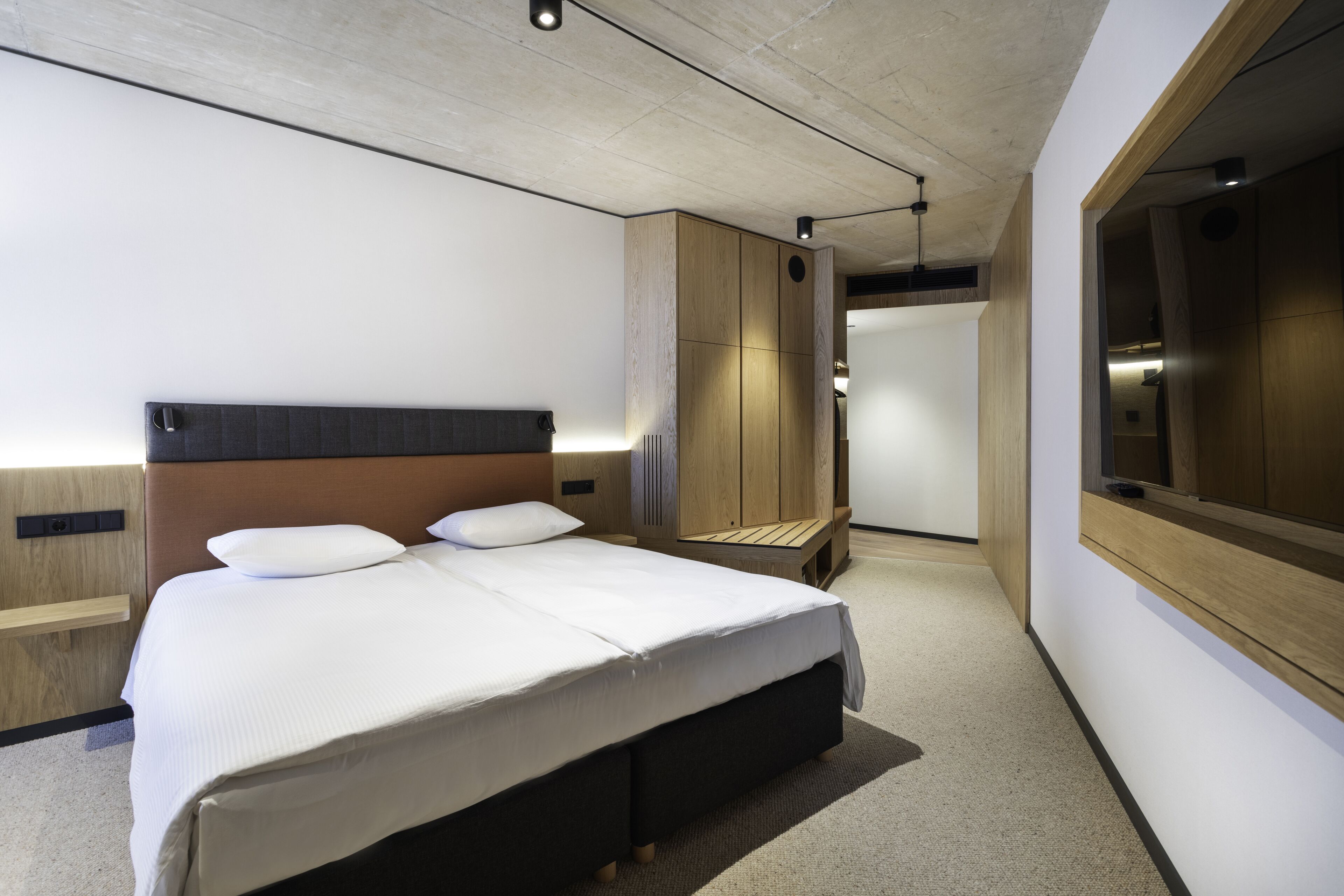 A modern hotel room with a large bed, built-in wardrobe, and a large mirror.