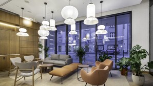Un vestíbulo moderno con sofá, sillones e iluminación colgante.