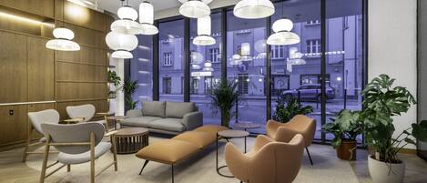 A modern lobby with a sofa, chairs, and hanging pendant lights.