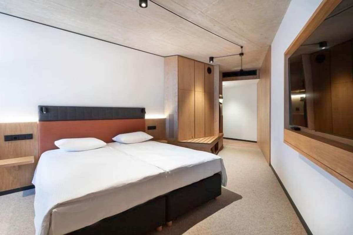A modern hotel room with a large bed, built-in wardrobe, and a large mirror.