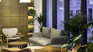 A modern living room with a sofa, chairs, and hanging pendant lights.