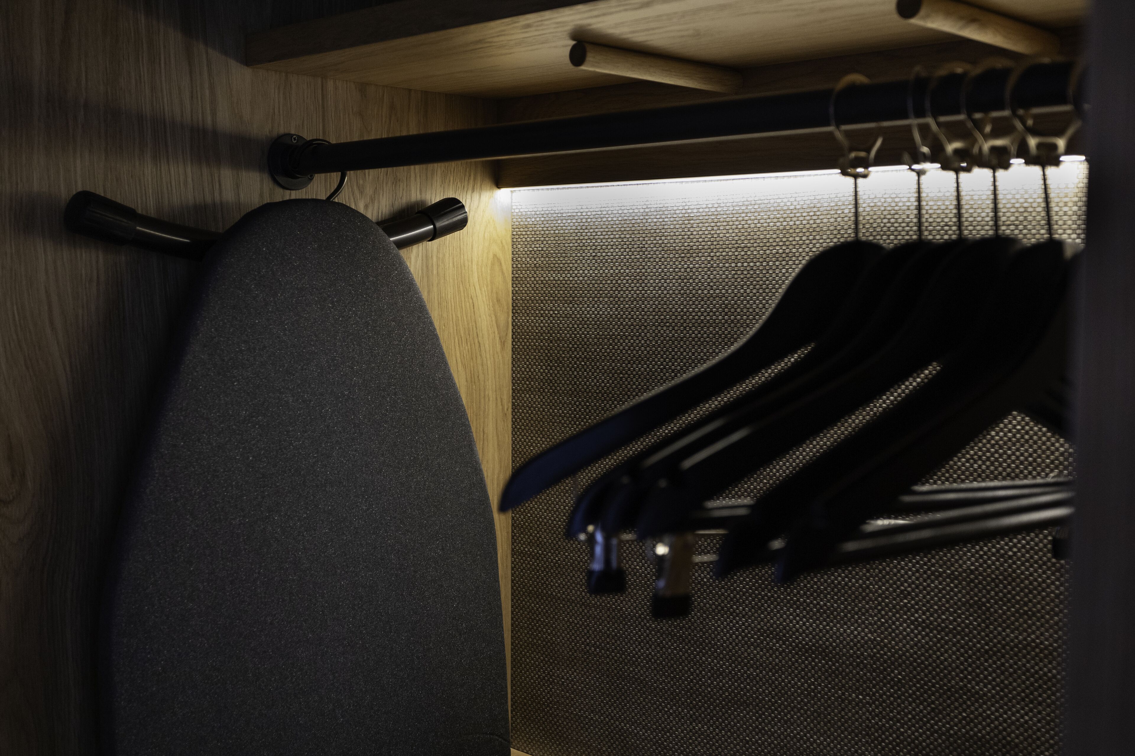 A closet with a grey chair and multiple hangers.