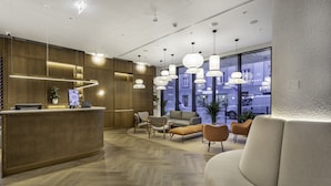 Un área de recepción moderna con un mostrador de madera, asientos cómodos e iluminación colgante.