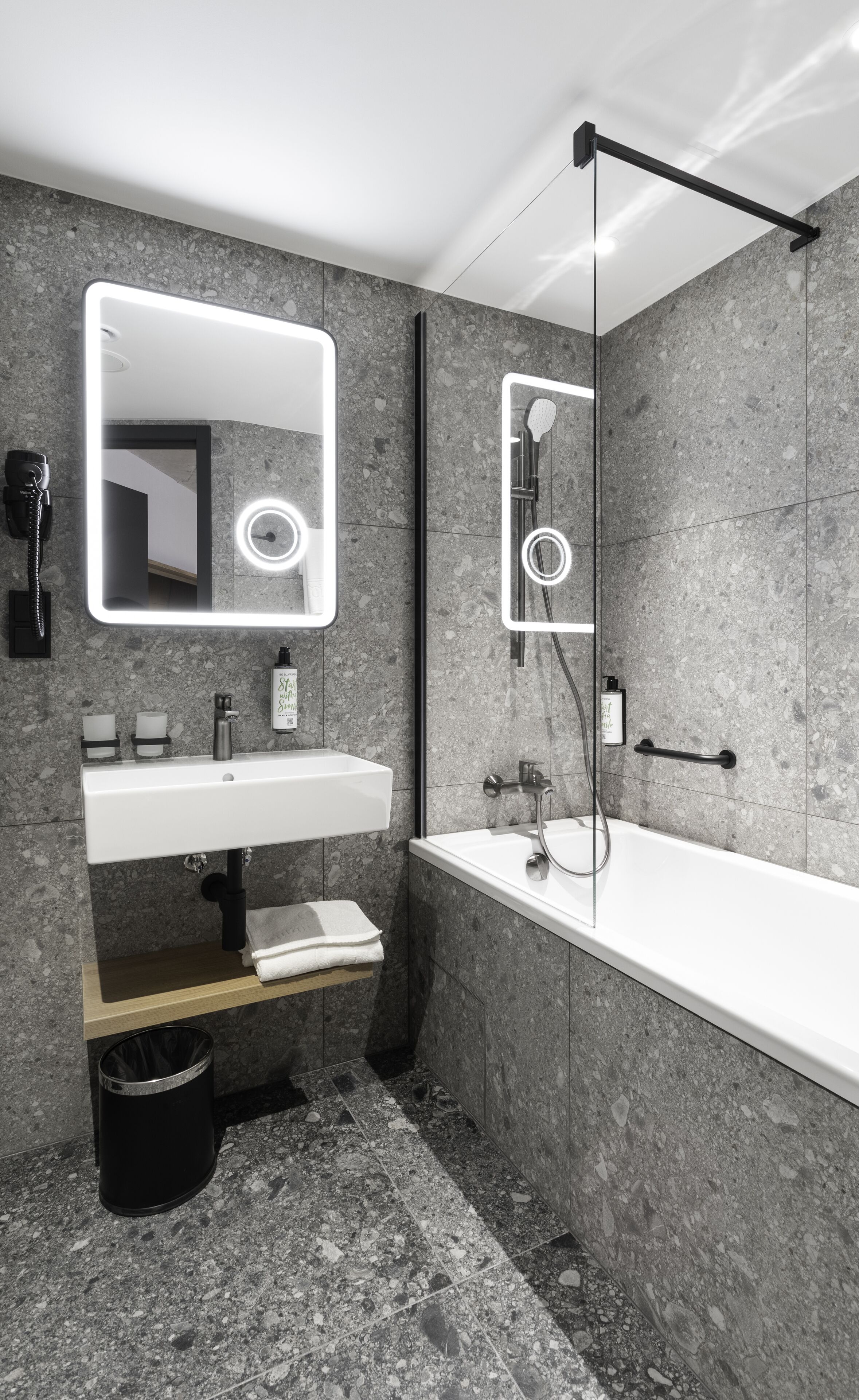 Een moderne badkamer met een grote spiegel, een wastafel, een badkuip en een douche.