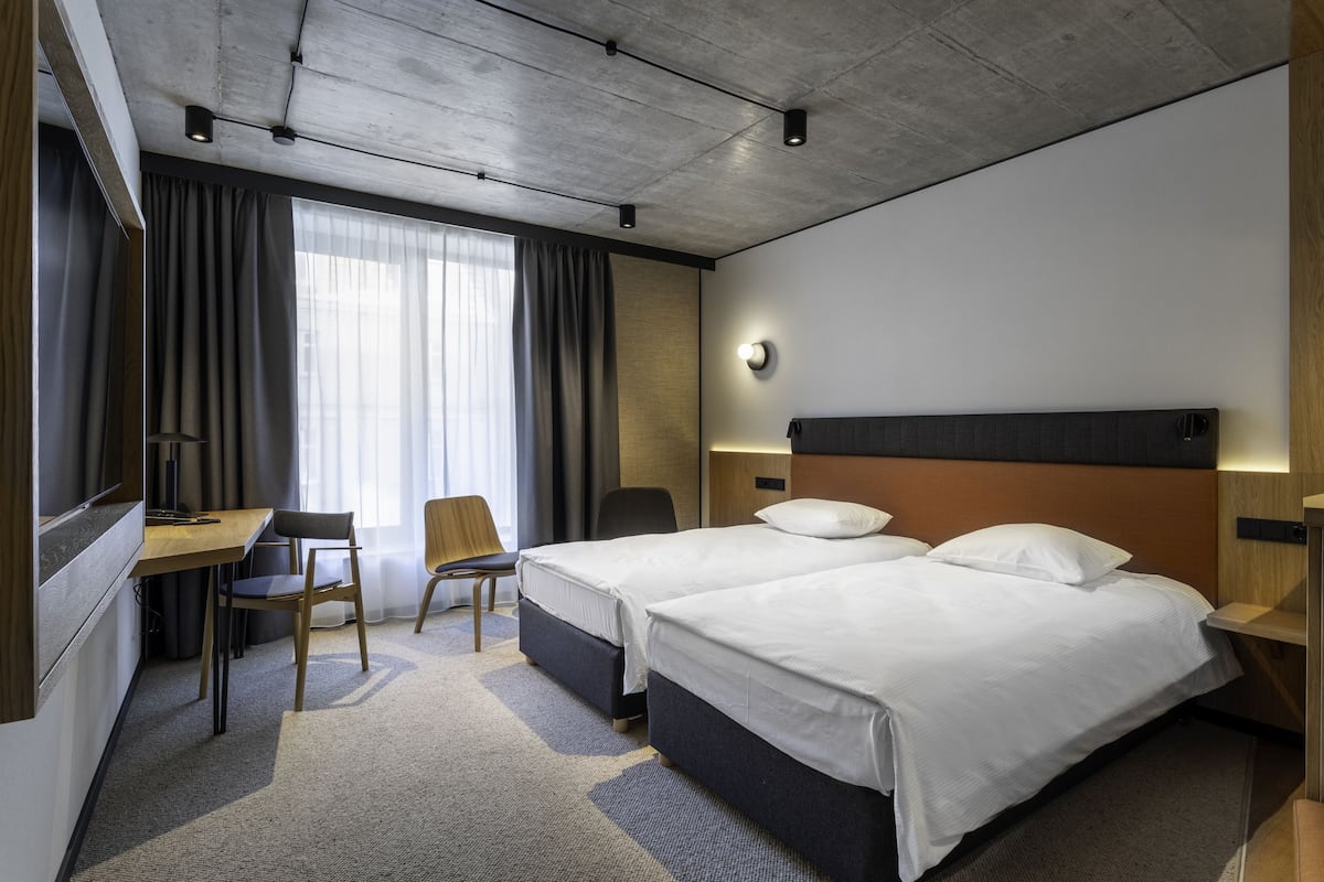 A hotel room with two beds, a desk, and a chair.
