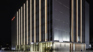 Un hotel moderno con un diseño vertical llamativo, amplias ventanas de vidrio y un área de entrada destacada.