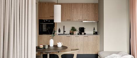 A modern, compact living space with a kitchenette, a dining area, and a bedroom.
