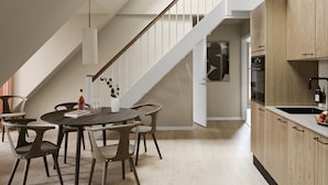 Una cocina moderna con armarios de madera, un lavamanos negro y una zona de comedor con una mesa redonda y sillas.