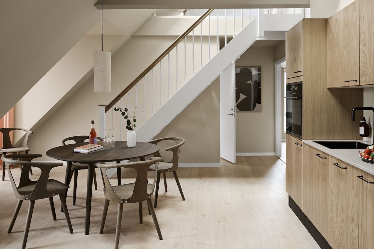 A modern kitchen with wooden cabinets, a black sink, and a dining area with a round table and chairs.