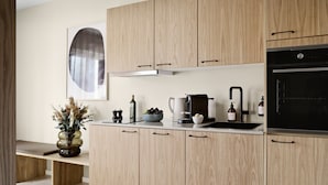 Una cocina moderna con armarios de madera, una cafetera, un lavamanos y un ventanal grande.