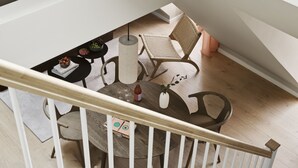 Un interior moderno con una escalera, una mesa redonda de comedor y una silla de mimbre.
