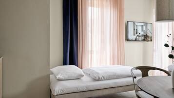 A modern bedroom with a bed, a round dining table, and a view of a room through a window.