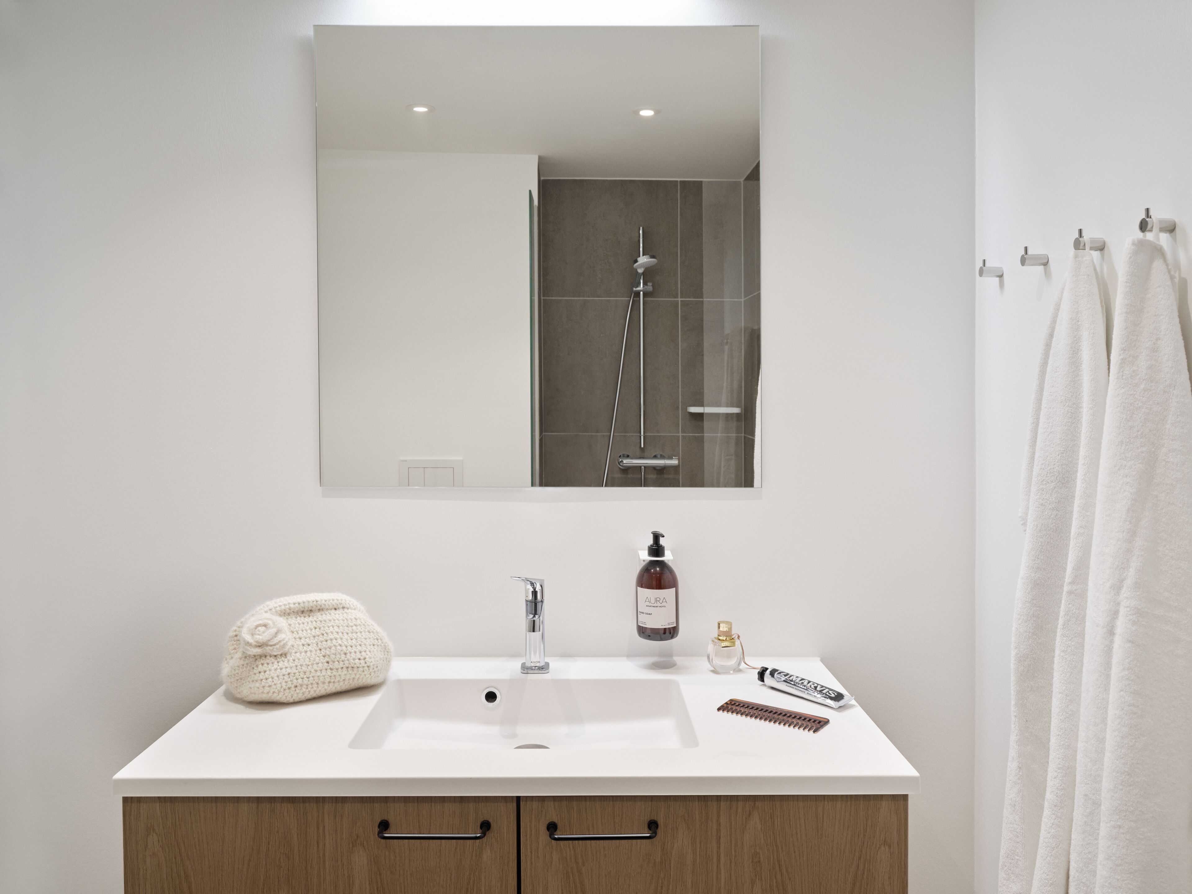 Un baño moderno con un lavamanos blanco, un mueble de madera y un espejo sobre el lavamanos.