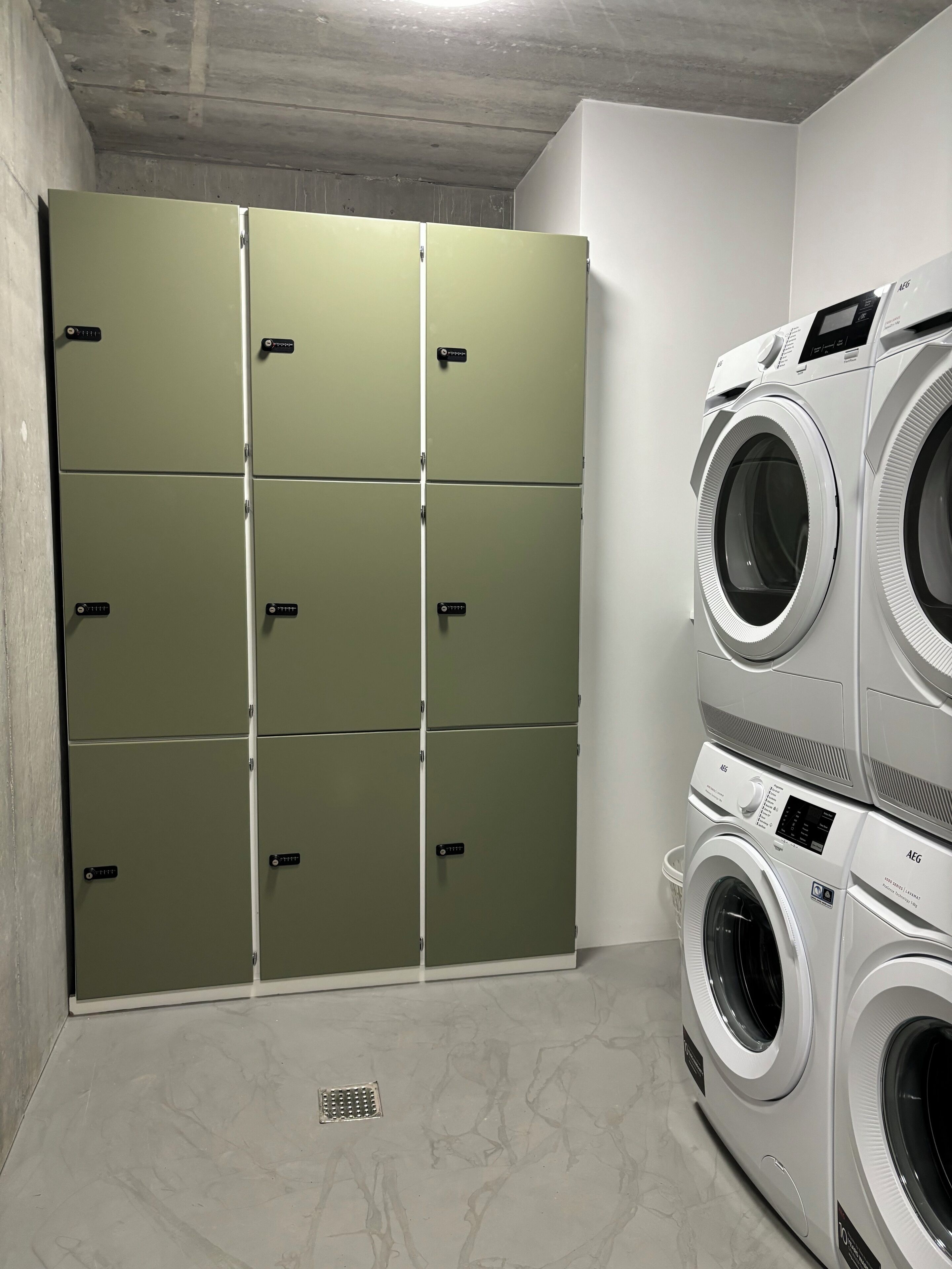 A laundry room with green lockers and stacked front-loading washing machines.