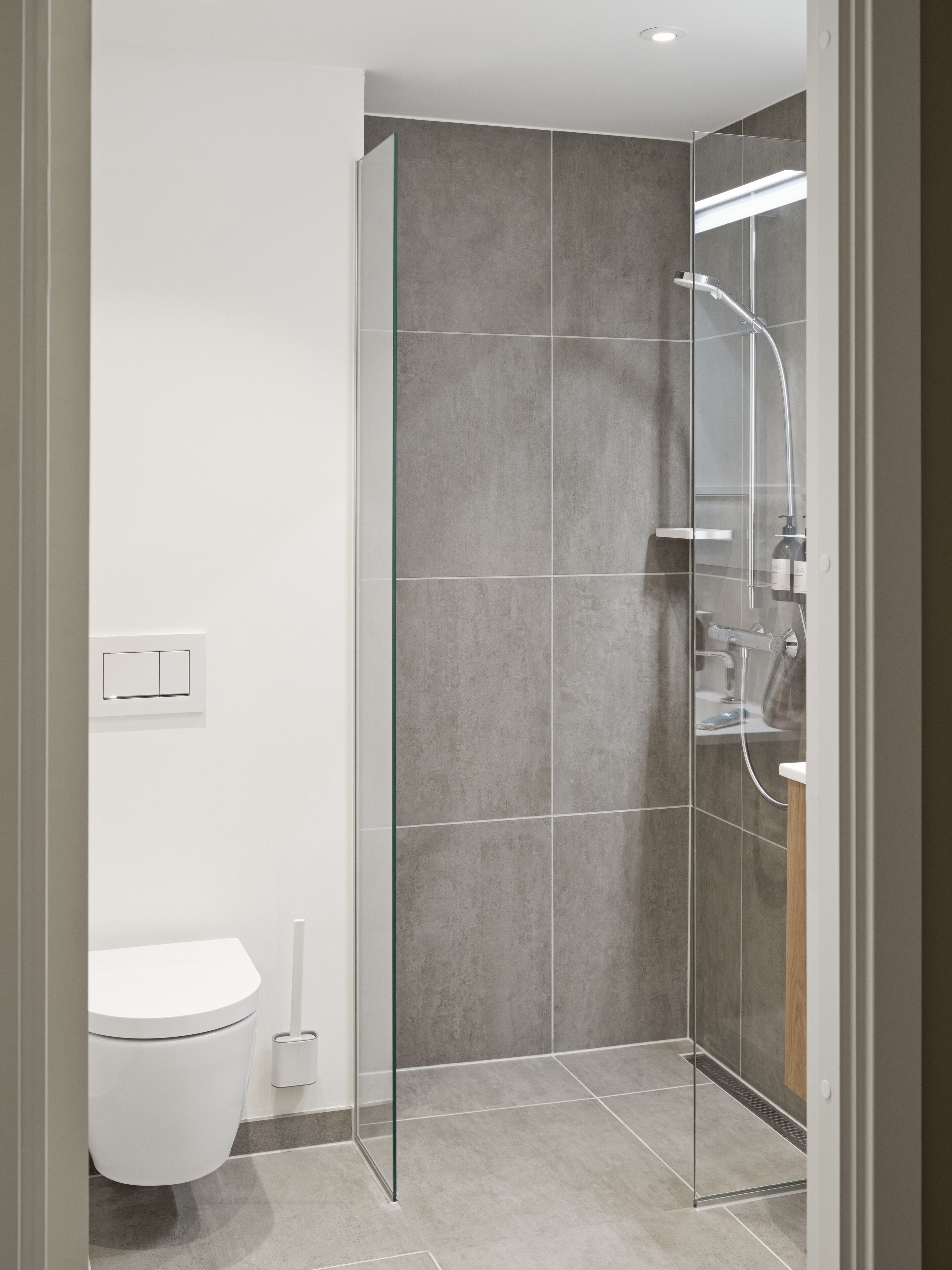 Ein modernes Badezimmer mit Duschkabine aus Glas, Toilette und Waschbecken.