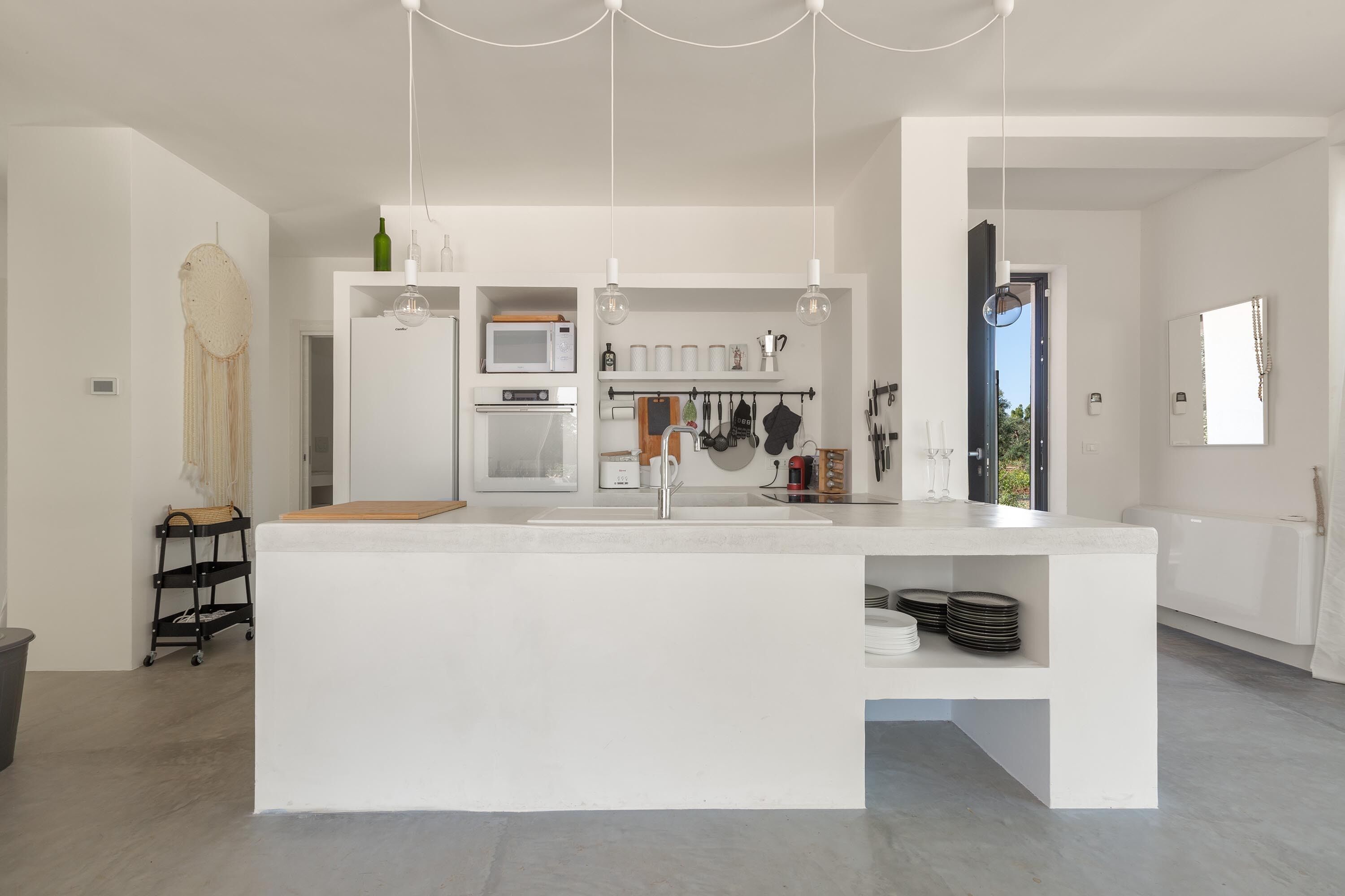 A modern kitchen with a central island, white cabinetry, and hanging pendant lights. - 3538 Villa Sylvia by Perle di Puglia (San Vito dei Normanni)