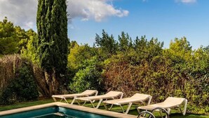 A rectangular swimming pool with a clear blue water surface, surrounded by a tiled deck. There are several lounge chairs aligned along the poolside. - Villa Sofía súper lujo (Valldemossa)