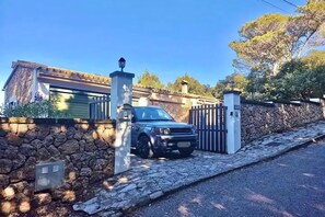 Surrounded by lush trees, this residence offers a secure entrance with a gated entrance and a metal gate.