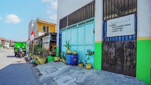 A building with a blue door, potted plants, and a sign with text. - OYO Life 93009 Griya Nautika Sedati (Sidoarjo)