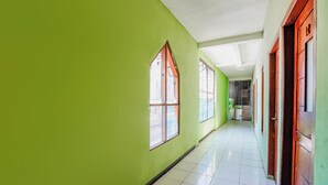 A hallway with green walls, white tiled flooring, and wooden doors. - OYO Life 93009 Griya Nautika Sedati (Sidoarjo)