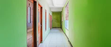 A corridor with green walls and wooden doors, leading to multiple rooms.