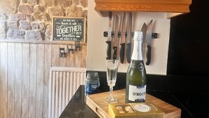 A kitchen counter with a bottle of O'Boc, a glass, and a box of chocolates. - Historic Countryside Cottage - Sleeps 3 & Pets Ok (Morecambe)