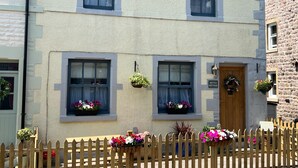 A two-story building with a stone facade, multiple windows with curtains, and a wooden door. - Historic Countryside Cottage - Sleeps 3 & Pets Ok (Morecambe)