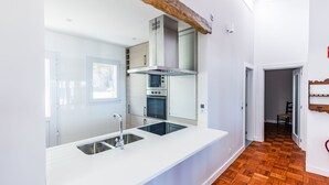 Eine moderne Küche mit weißen Schränken, einer zentralen Kochinsel inklusive Spüle und einem eingebauten Backofen.