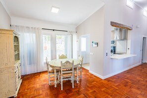 Un comedor con una mesa redonda y sillas, un armario de madera, y una zona de cocina con encimera y fregadero.