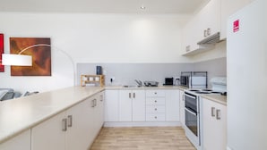 A modern kitchen with white cabinetry, a wooden countertop, a built-in oven, and a microwave.