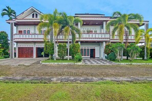 A two-story building with a symmetrical facade, a central entrance, and a paved driveway. - OYO 91852 Prima Guesthouse Syariah (Padang)