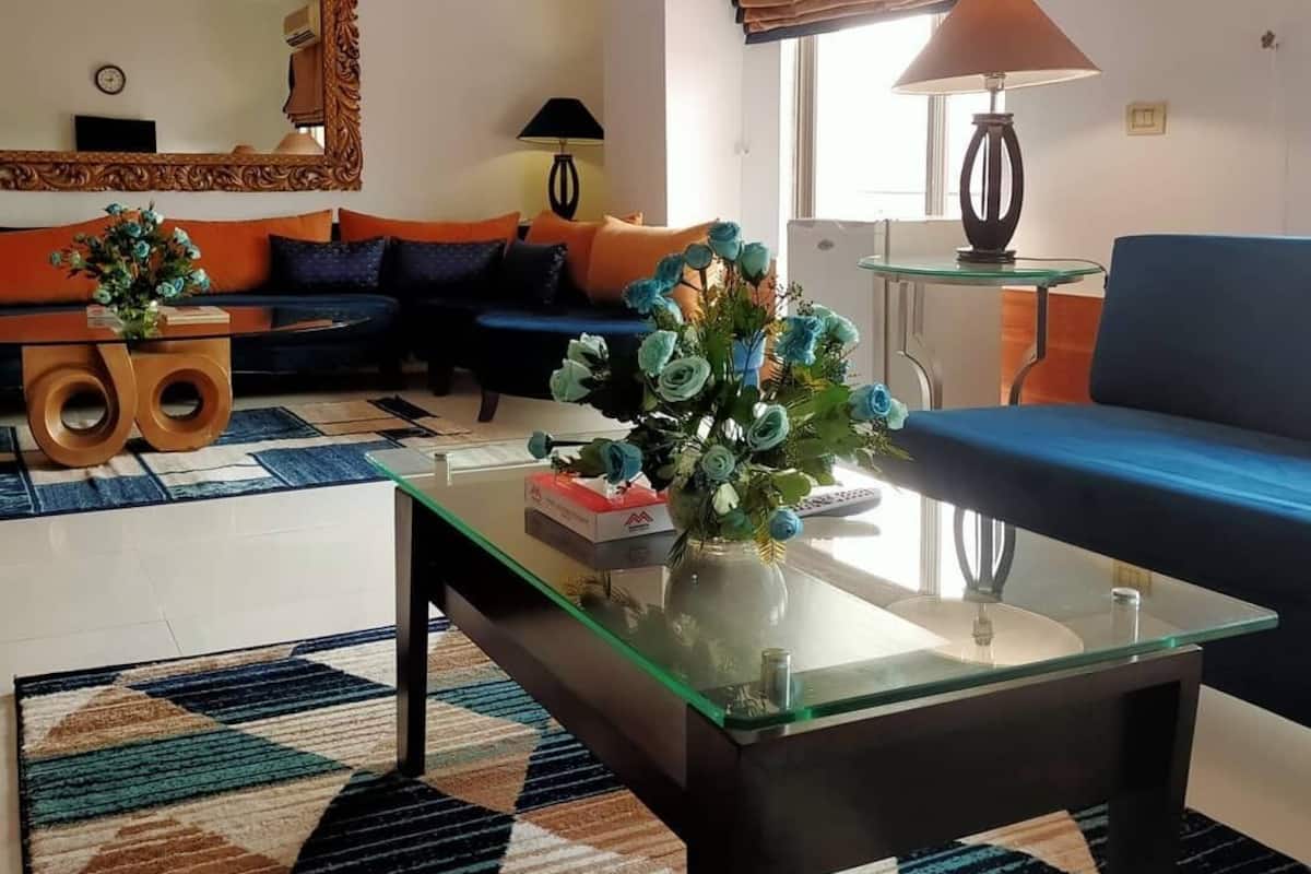 Een woonkamer met een bank, een bijzettafeltje, een spiegel en een lamp.