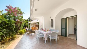 An outdoor patio with a dining table set for four, surrounded by white chairs. - 3582 Villetta Delle Cale by Barbarhouse (Ostuni)