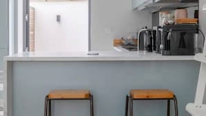 Una cocina moderna con un ventanal grande, dos taburetes y una cafetera.