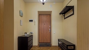 A hallway with a wooden floor, a black desk, a wooden door, and a black shelf with a mirror. - Stylish apartment near the railway station (Minsk)